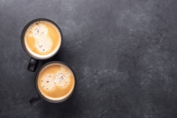 Two cups with coffee on dark stone background. Top view. Copy space