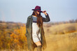 © maxbelchenko - Elegant woman in coat with hat walks in autumn park. Stylish woman enjoying autumn weather in the meadow. Autumn fashion. Rest, relaxation, lifestyle concept.