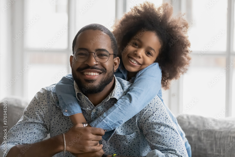Portrait of cute little ethnic girl hug smiling african American young father show love and affection, happy biracial dad and small daughter hug cuddle, enjoy tender close family weekend together - obrazy, fototapety, plakaty 