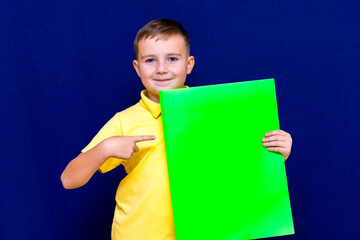 Happy calm caucasian child boy holding a poster for your information on the blue background