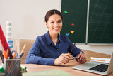 Fototapeta  - Smiling female teacher using laptop in class room
