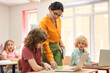 © Yakobchuk Olena - Elegant female teacher explaining work on laptop to children