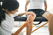 © Louis-Paul Photo - physiotherapist doing treatment with patient in bright office check knee