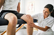 © Louis-Paul Photo - physiotherapist doing treatment with patient in bright office check knee