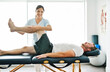 © Louis-Paul Photo - physiotherapist doing treatment with patient in bright office with leg training