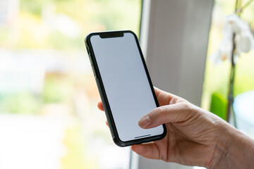 Woman hand holding the black smartphone with blank screen and modern frameless design Frau hält Smartphone in der Hand