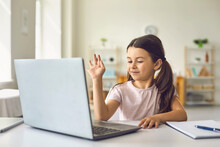 Child Online. A Little Girl Uses A Laptop Video Chat To Communicate Learning While Sitting At A Table At Home.