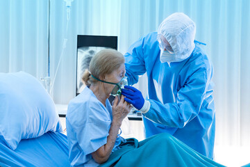 Medical team giving oxygen mask to the elderly covid-19 patient in  quarantine room. Poor women are suffering from a lung infection in restricted areas. Part of coronavirus 2019-2020 global pandemic
