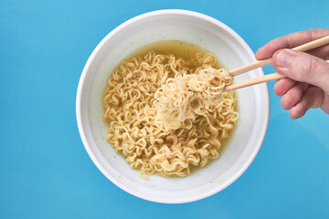 instant noodles at white bowl over blue background with copy space. fast food concept. flat lay