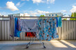 Suszarka z praniem stoi na balkonie, słoneczny dzień. 