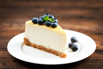 Wall Mural - Slice of cheesecake with blueberries isolated on wooden table background