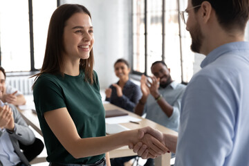 Wall Mural - Close up executive shaking successful businesswoman hand at meeting, diverse colleagues applauding, team leader thanking worker for good work result, achievement, congratulating with promotion