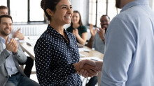 Close Up Executive Shaking Smiling Indian Businesswoman Hand At Meeting, Diverse Colleagues Applauding, Team Leader Congratulating Successful Employee With Job Promotion, Thanking For Good Work