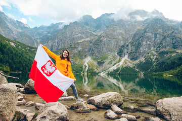 Poster - young pretty smiling woman holding poland flag at beach of mountain lake