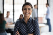 © fizkes - Head shot portrait close up smiling confident beautiful Indian businesswoman standing in modern office room with arms crossed, successful executive team leader mentor posing for corporate photo