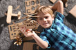 © New Africa - Little boy playing with cardboard helicopter on floor at home, top view. Creative hobby