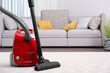 Modern red vacuum cleaner on carpet indoors, space for text