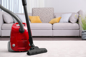 Sticker - Modern red vacuum cleaner on carpet indoors, space for text