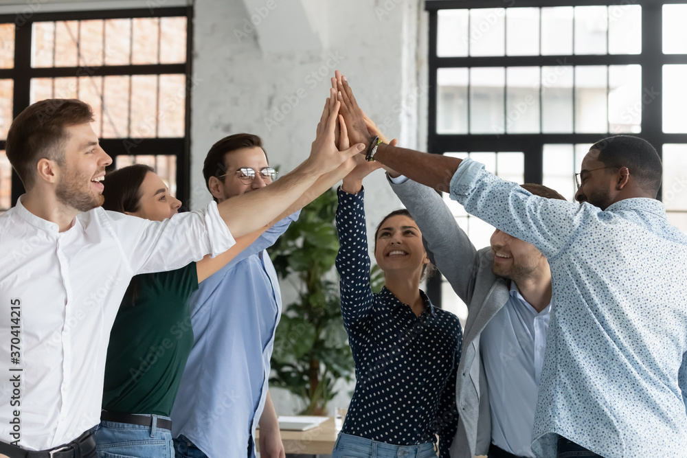 Overjoyed successful young diverse employees giving high five at ...