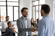 Close up team leader thanking successful employee for good work at meeting, diverse colleagues applauding, cheering, executive shaking smiling businessman hand, congratulating with promotion
