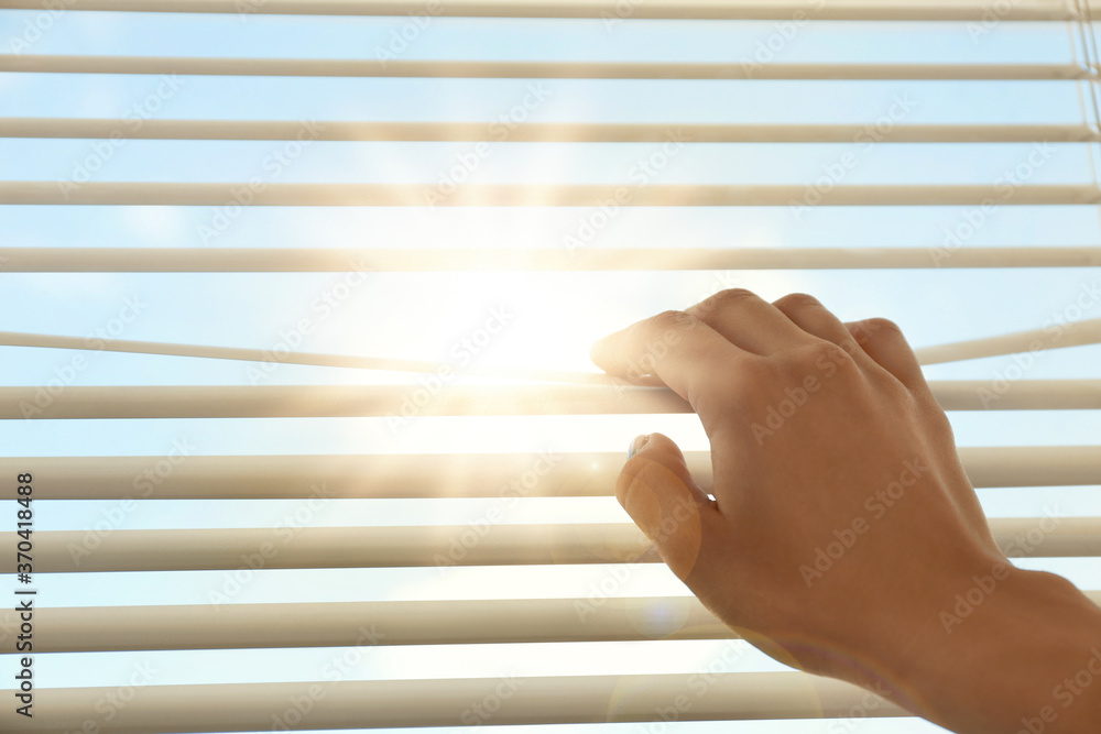 Woman opening window blinds on sunny morning, closeup - obrazy, fototapety, plakaty 