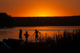 Fototapeta Fototapety pomosty - Dzieci kąpią się w jeziorze podczas widowiskowego zachodu słońca