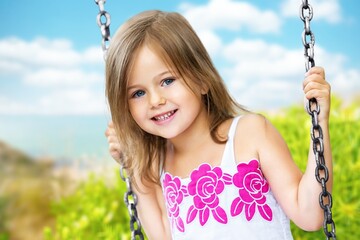 Little child blond girl having fun on a swing