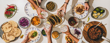 Friends Having Mexican Taco Dinner. Flat-lay Of Beef Tacos, Tomato Salsa, Tortillas, Beer, Snacks And Peoples Hands Clinking Glasses Over White Table, Top View. Mexican Cuisine, Comfort Food Concept