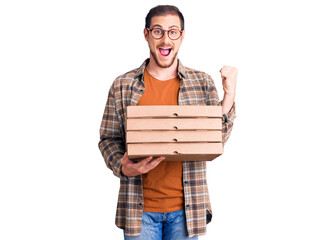 Young handsome caucasian man holding delivery pizza box screaming proud, celebrating victory and success very excited with raised arms