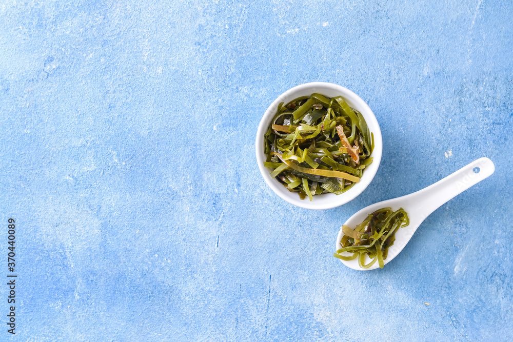 Bowl with tasty seaweed on color background