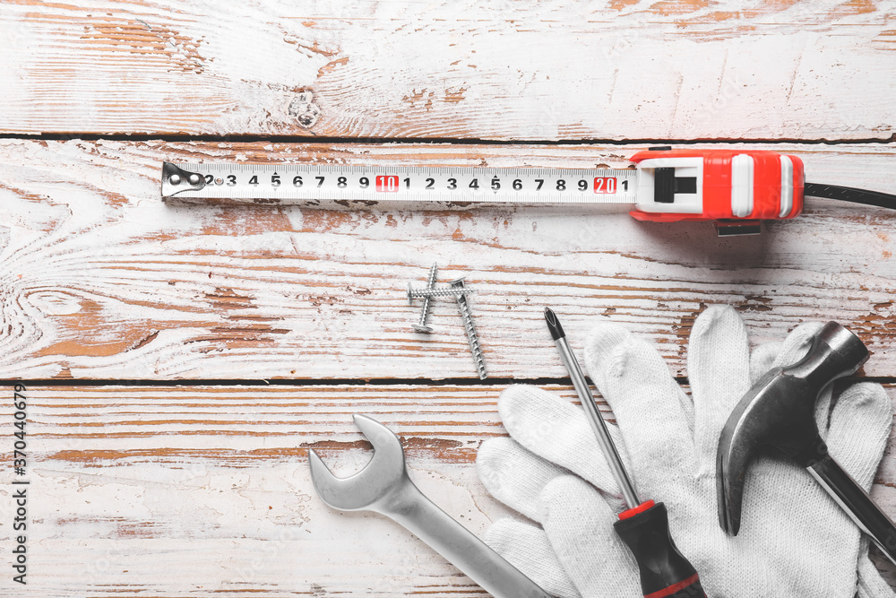 Measuring tape with builder's supplies on wooden background