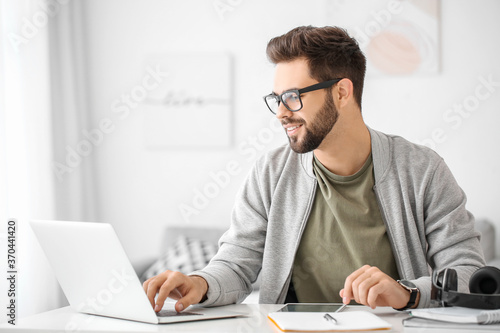 Fotomural Young man using laptop for online learning at home