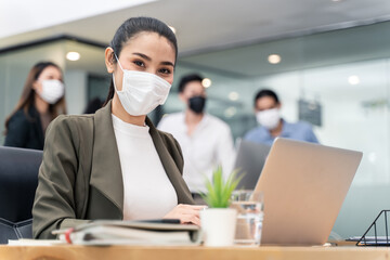 Asian young businesswoman wearing mask working on computer in office.