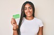 © Krakenimages.com - Young african american woman with braids holding birth control pills looking positive and happy standing and smiling with a confident smile showing teeth