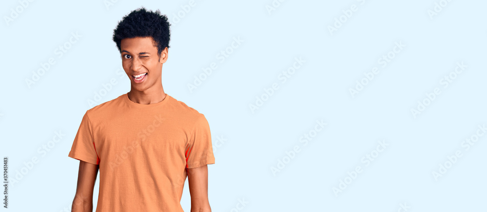 Young african american man wearing casual clothes winking looking at the camera with sexy expression, cheerful and happy face.