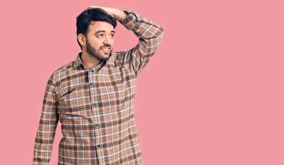 Young hispanic man wearing casual clothes smiling confident touching hair with hand up gesture, posing attractive and fashionable