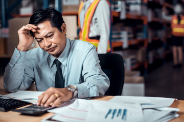 Stressed businessman worry about financial balance trouble of his company at his office in warehouse. Profit less than target while global corona virus or Covid-19 crisis, negative emotional concept