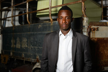 Wall Mural - Young African businessman in suit against old pickup truck