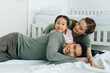 © twinsterphoto - Cheerful Asian mother and father with young daughter lying on bed with smiles at home. Happy and carefree family with one child concept.