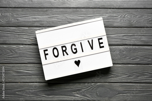 Fotomural Board with word FORGIVE on wooden background