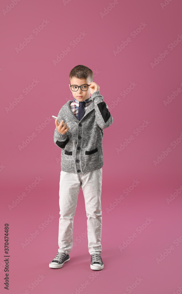Cute little boy with mobile phone on color background