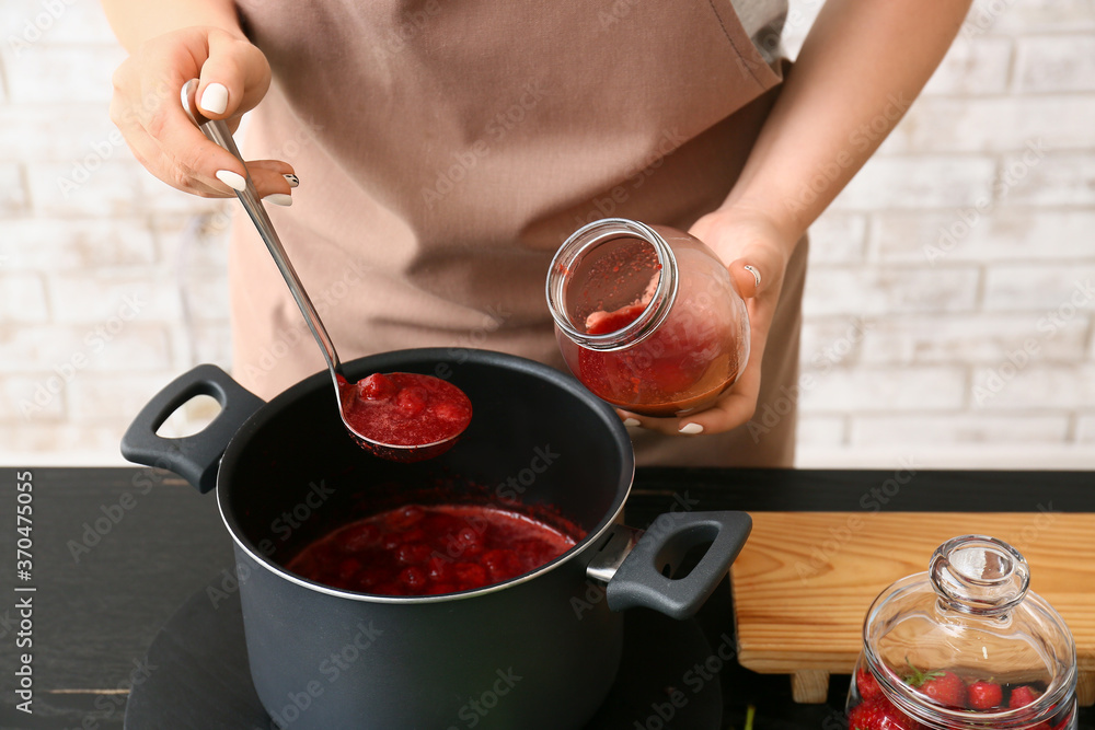 Woman making sweet strawberry jam in kitchen - obrazy, fototapety, plakaty 