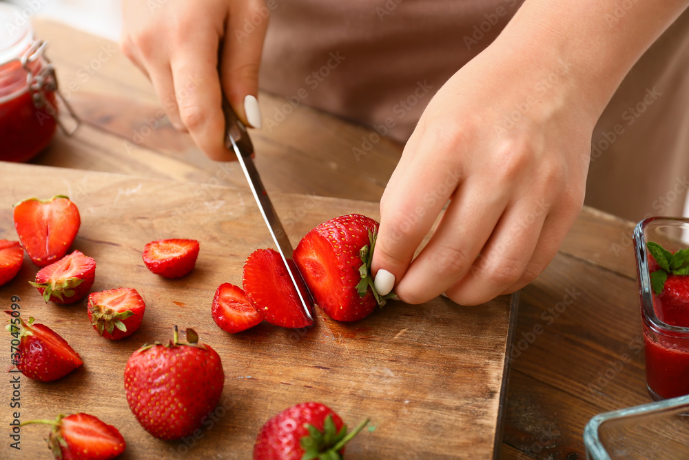 Woman making sweet strawberry jam in kitchen, closeup