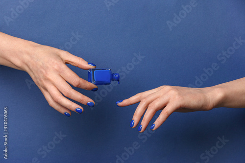 Hands with nail polish on color background