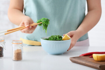 Woman eating tasty seaweed salad at table