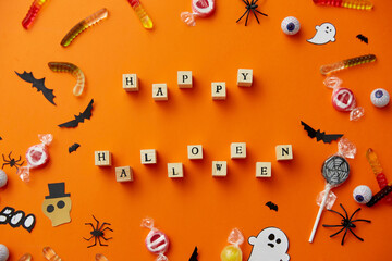 Wall Mural - halloween and holiday concept - wooden toy blocks with trick or treat lettering candies and decorations on orange background