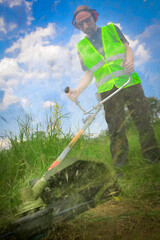 Wall Mural - Worker mowing grass with grass trimmer