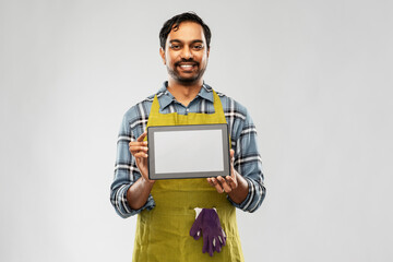 Poster - gardening, farming and technology concept - happy smiling indian male gardener or farmer in apron showing tablet pc computer over grey background