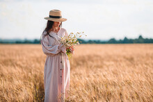 Back View Of Girl In Wheat Field. Beautiful Woman In Dress In A Straw Hat