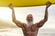 © Alessandro Biascioli - Happy fit senior having fun surfing at sunset time - Sporty bearded man training with surfboard on the beach - Elderly healthy people lifestyle and extreme sport concept